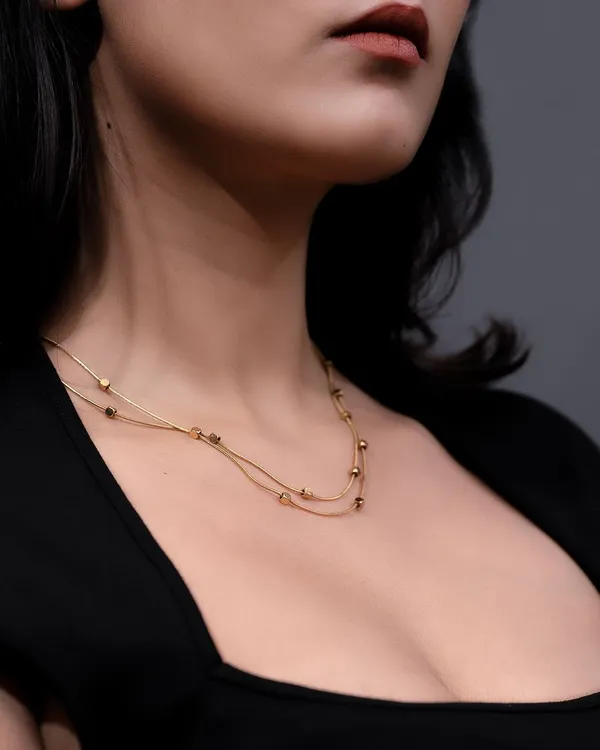 A model wearing a delicate, layered gold necklace. Showing jewelry on a model provides context, demonstrates scale, and helps customers visualize how it will look.