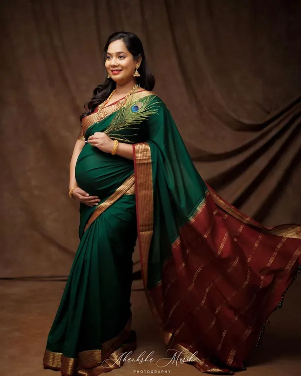 Draped in a magnificent green and red silk saree, this mother-to-be is the picture of grace and tradition. The peacock feather is a beautiful touch, symbolizing royalty and beauty.
