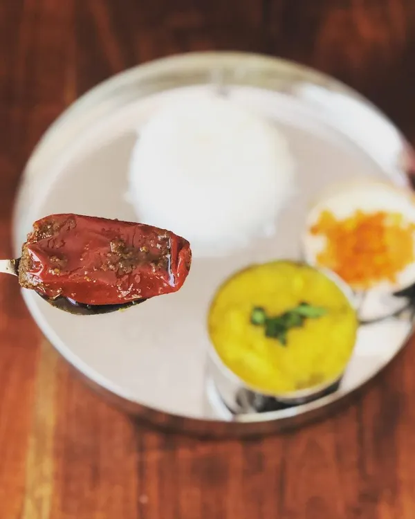 A single spoonful of my Bharwan Mirchi, or stuffed red chili pickle, served over a traditional Indian thali. The rich red color comes from the chilies and spices, with no artificial colors added.