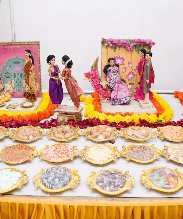 A glimpse into the world of a traditional Maharashtrian baby shower, or *dohale jevan*. This elaborate 'rukhwat' display features handcrafted dolls depicting family scenes, surrounded by floral decorations and traditional sweets, creating a beautiful centerpiece for the celebration.