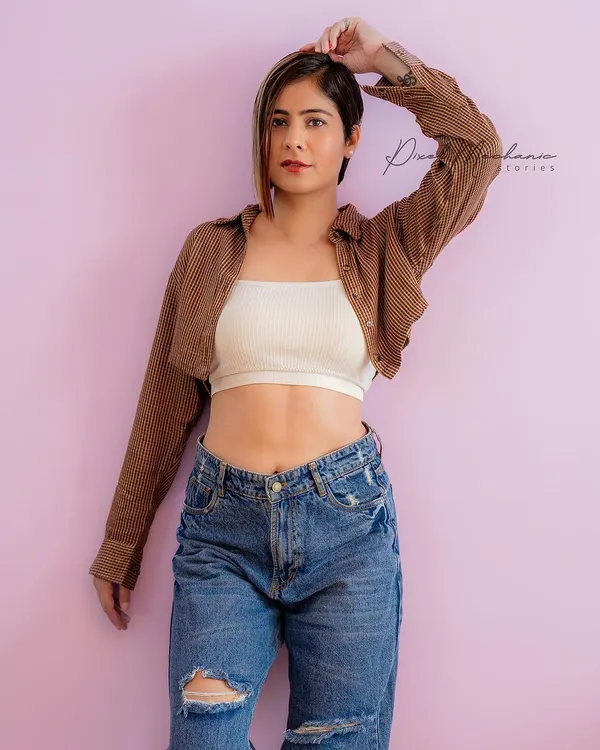 A simple, confident studio look. The clean background and modern styling with a crop top and jeans are perfect for building a model portfolio or for a bold personal branding shoot.
