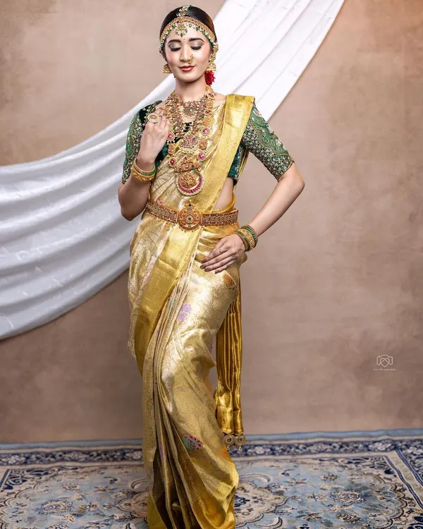 A complete South Indian bridal look. We designed the heavily embroidered green velvet blouse to pair with this stunning golden tissue Kanjeevaram saree for a grand and traditional Muhurtham ceremony.