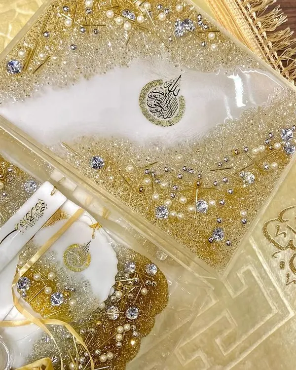 An elegant gift set in white and gold, perfect for Eid or any special occasion. This set includes a resin Quran box, a matching bookmark, and other accessories, all embellished with crystals and pearls for a luxurious finish.