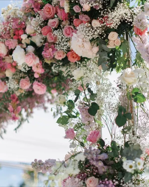 A close-up of the lush floral arrangement from a pastel-themed wedding stage. This detailed shot shows the beautiful combination of pink roses, white baby's breath, and fresh eucalyptus, highlighting our skill in floral artistry.