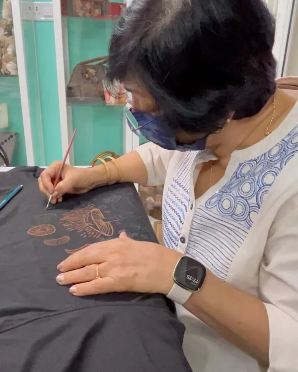 A participant carefully painting a mushroom design onto a t-shirt using bleach. The precision is incredible.