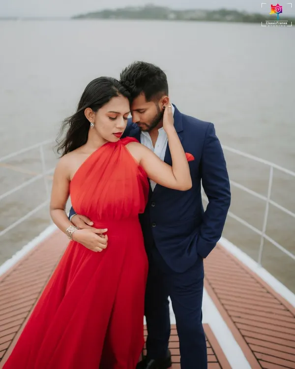 A bold and stylish portrait on a yacht in Goa. The vibrant red dress against the blue water and sky creates a striking, high-fashion look for a destination pre-wedding shoot.
