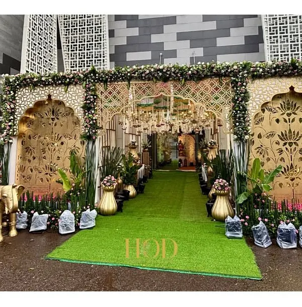 A truly grand entrance for a royal wedding, featuring intricate golden jali work, lush greenery, and auspicious elephant statues to welcome guests with traditional elegance.