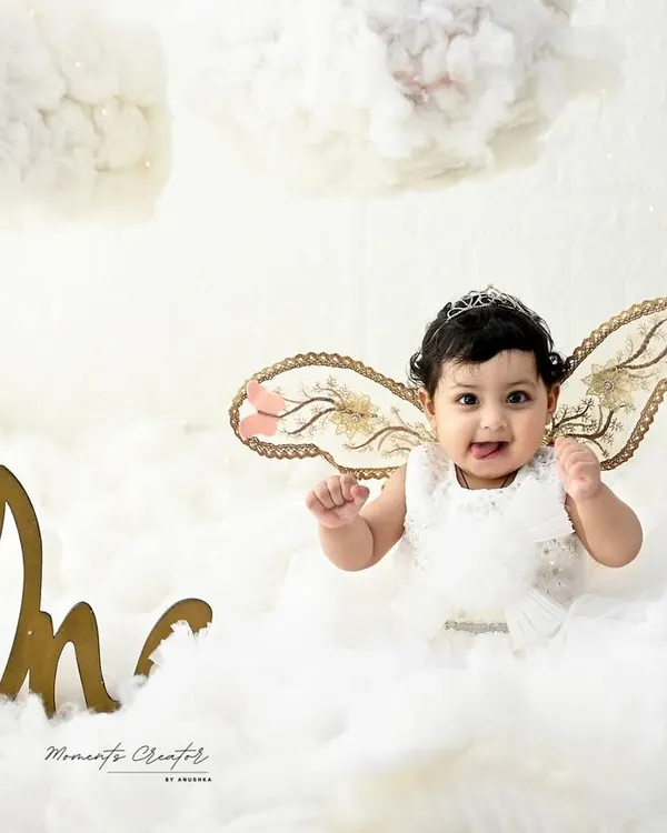 A little angel floating on a cloud. With delicate, shimmery wings and a happy smile, this baby girl looks absolutely heavenly in this all-white, dreamy setup.