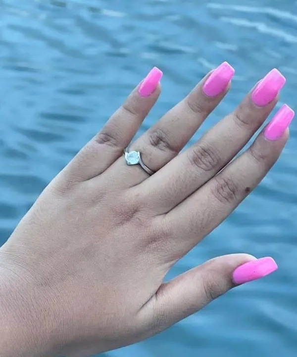 A vibrant, eye-catching neon pink gel polish on long, square-shaped extensions. This color is perfect for vacations, parties, or anytime you want your nails to be the center of attention.