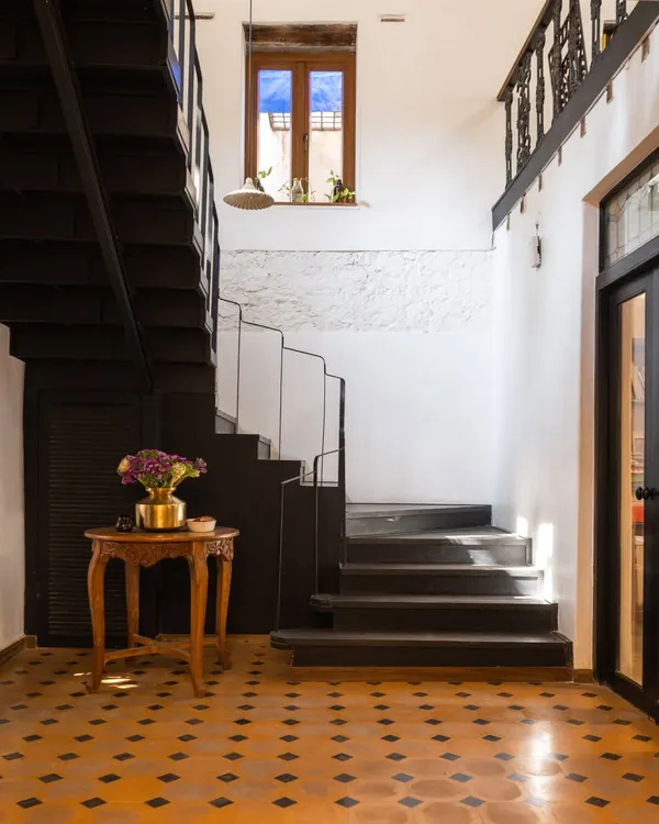 When I first stepped into this 80-year-old structure, I saw a quiet soul beneath the rubble. This staircase and entryway, with its original tiled floor and restored wooden details, is a glimpse into the journey of bringing our studio back to life.