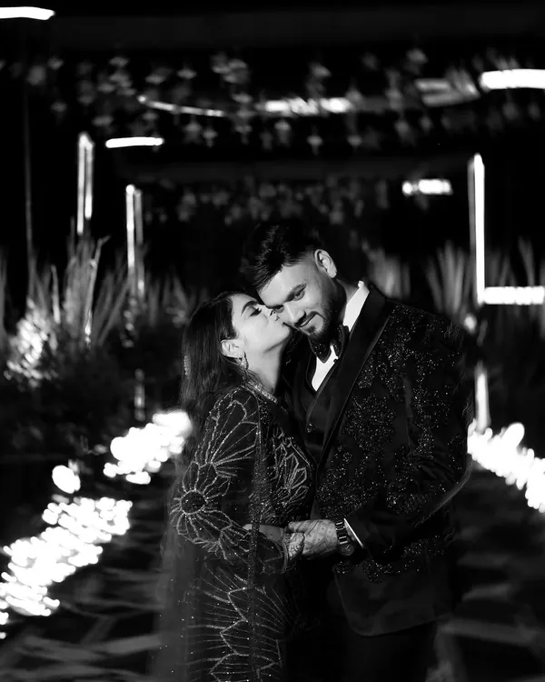 A timeless black and white portrait. The bride's gentle kiss on the groom's cheek, the soft lighting, and the classic monochrome finish create an image that is pure romance.