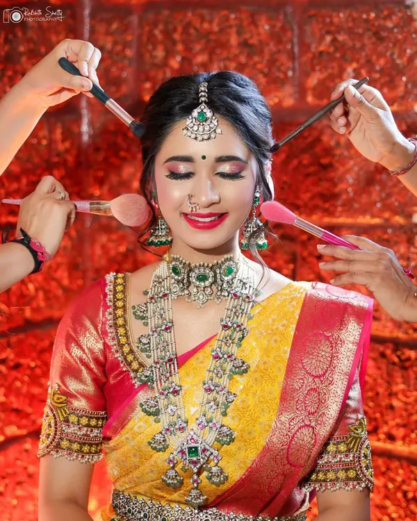 This is what my happy place looks like. I love collaborating with talented makeup artists to create flawless bridal looks. This shot captures the joy and artistry of getting ready, focusing on the stunning details of the makeup and heavy temple jewelry.