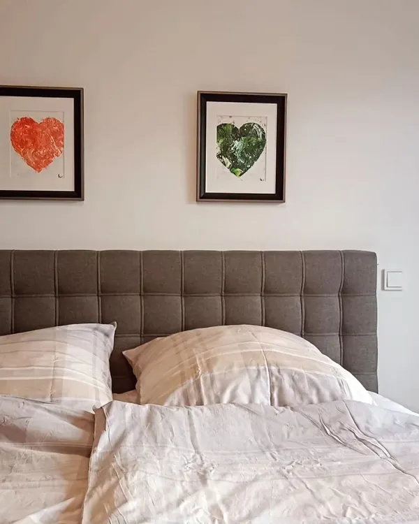 A pair of my textured heart paintings, one in red and one in green, hanging above a client's bed. They create a beautiful, balanced focal point, bringing colors of passion and nature into a calm, neutral space.