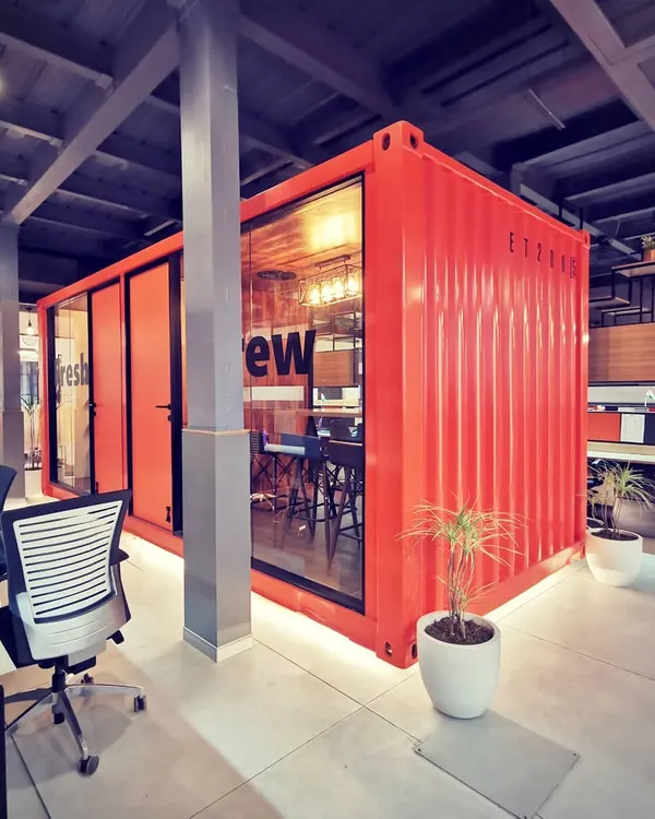 This is the centerpiece of our award-winning Tata Hitachi dealership design. We repurposed an actual shipping container into a fully functional, glass-walled meeting room, creating a bold statement about industrial aesthetics and innovative workspace solutions.