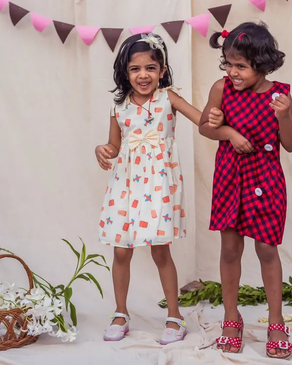 Double the fun, double the style! This video shows two happy girls in their comfortable and playful dresses, one in a quirky print and the other in a classic red and navy check.