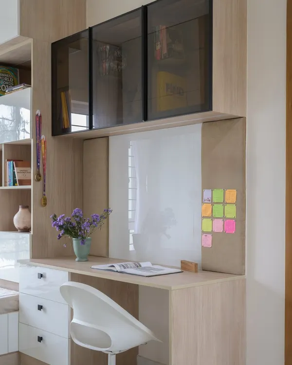 This study area for a young girl includes a whiteboard, pinboard, and ample desk space. The overhead cabinets with smoked glass provide stylish storage for books and supplies.