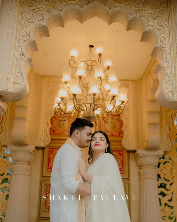 A moment of royal romance under a grand chandelier. The warm light and intricate details of the palace create a luxurious setting for this intimate couple portrait.