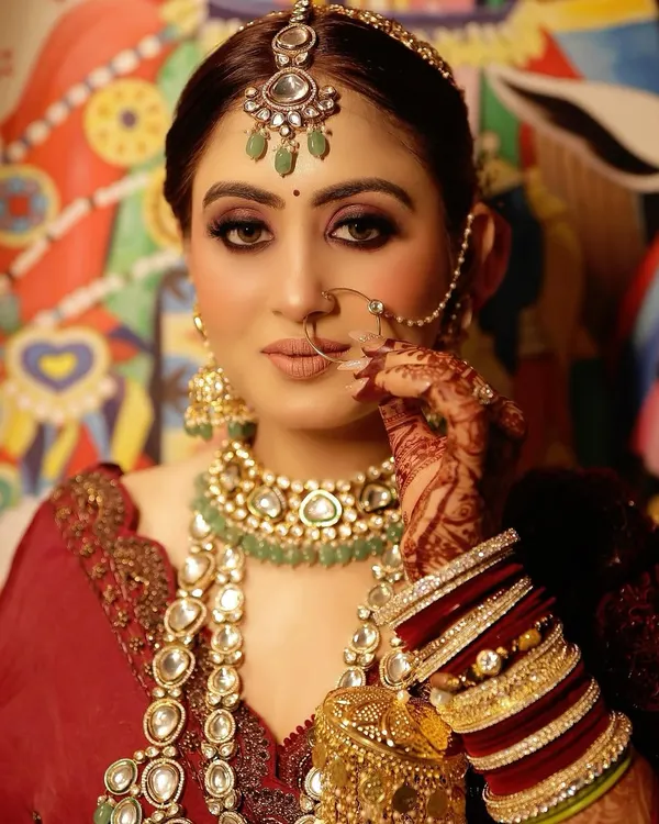 This is the quintessential royal bridal look I love to create. I focused on giving her a flawless, radiant base with bold, kohl-rimmed eyes and a perfectly defined lip, ensuring the makeup beautifully complements her magnificent jewellery and the richness of her red attire.