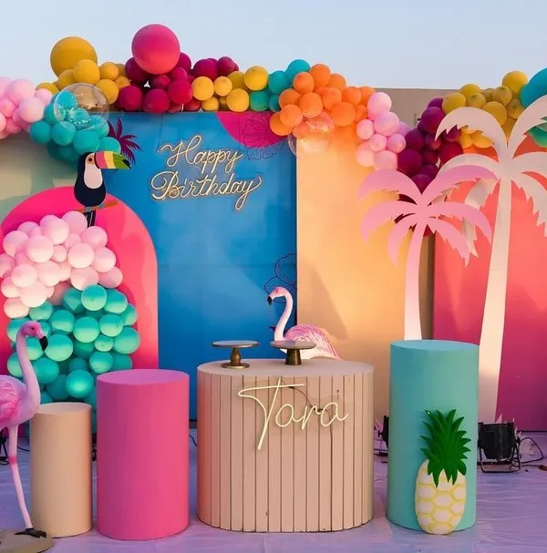 This vibrant tropical flamingo theme is perfect for a fun and colorful celebration. The setup includes custom-arched backdrops, a multi-colored organic balloon arch, themed props like flamingos and toucans, and a personalized cake stand.