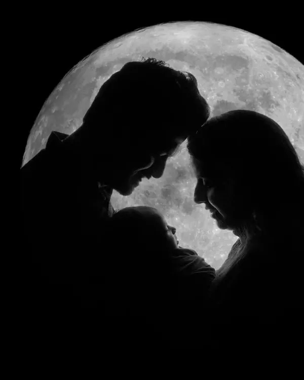 A new family silhouetted against a full moon, creating a timeless and artistic family portrait that feels like a dream.