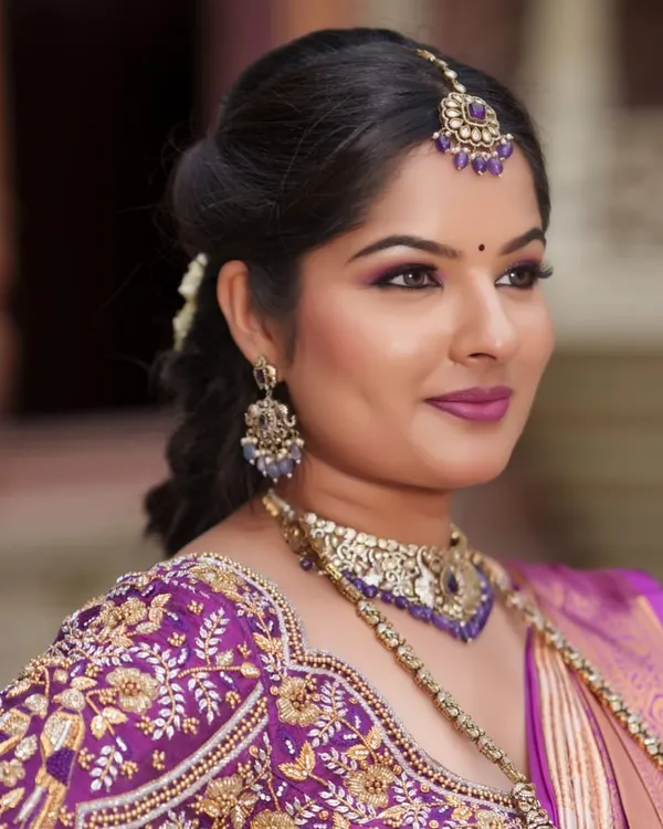 A close look at a purple bridal blouse with detailed zardozi embroidery. The craftsmanship is designed to complement a rich silk saree for a complete muhurtham or reception look.