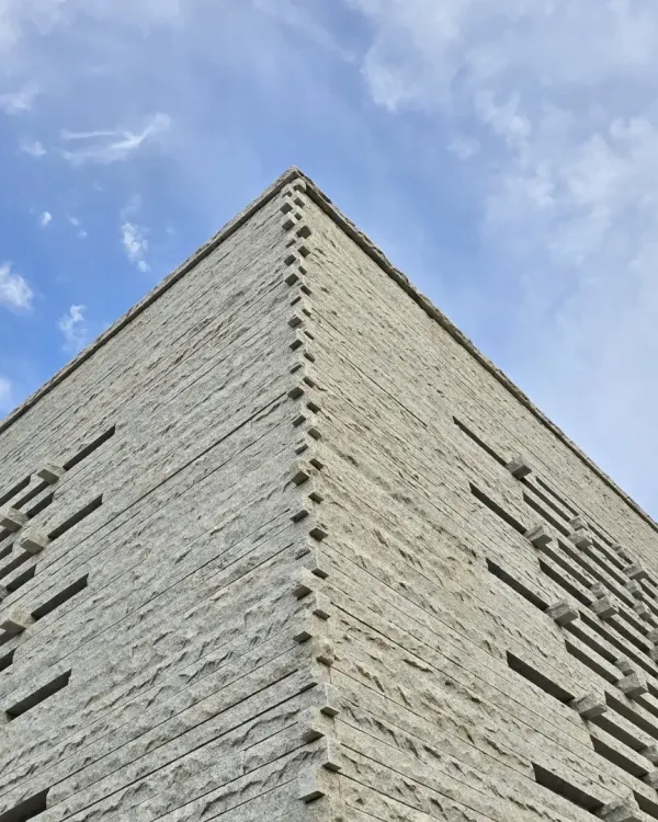 Our Tiruppur house is a symphony in stone. This upward shot shows the corner detail of the granite facade, where the texture of the stone meets the clean geometry of the sky.