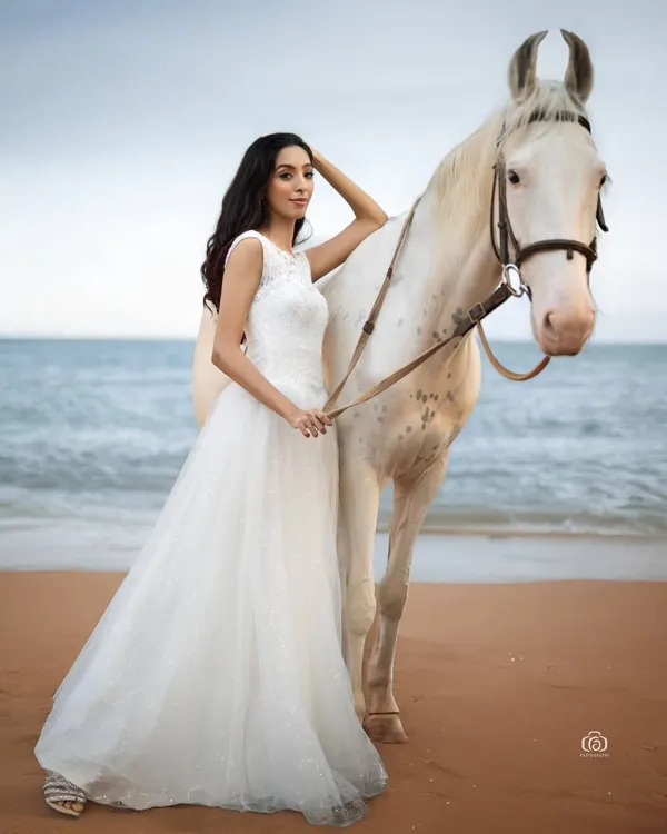 This shot combines the elegance of a flowing white gown with the raw beauty of a natural beach setting. Capturing the connection between the model and the horse required precise timing and an understanding of natural light to create this fairytale-like fashion portrait.