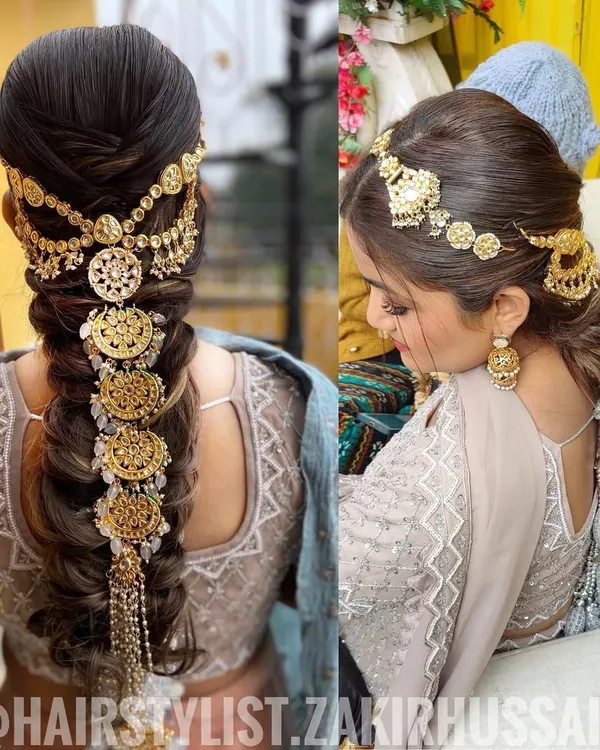 This is a stunning example of a traditional bridal braid heavily accessorized with intricate gold jewelry. The style is both regal and dramatic, perfect for making a grand entrance on your wedding day.