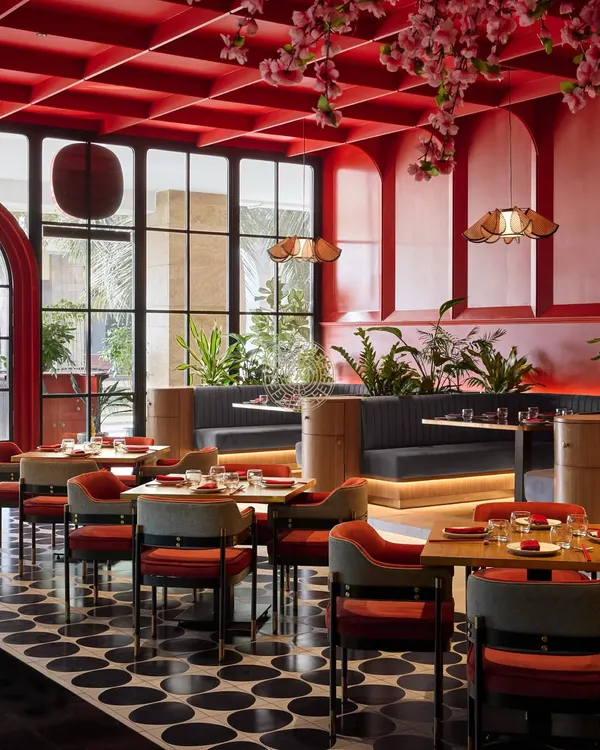 The dining area at Foo, where a bold red coffered ceiling and cherry blossoms create a dramatic, immersive atmosphere. The design balances traditional Asian color symbolism with a modern execution.