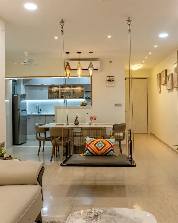 A full tour of a stunning 3BHK home where every room is crafted for comfort and style. This view shows the open-plan living and dining area, complete with a statement swing and a custom crockery unit, designed for a family of four.