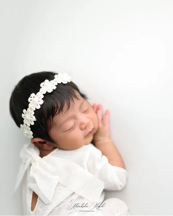 A portrait of pure serenity. This little one is posed to showcase their delicate features and peaceful sleep, using a simple white-on-white setup for a timeless and classic newborn photograph.