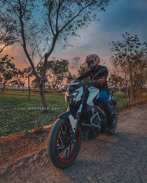 A rider on his white Dominar, pausing to enjoy a stunning sunset over the tea gardens of North Bengal. We always make time to appreciate the view.