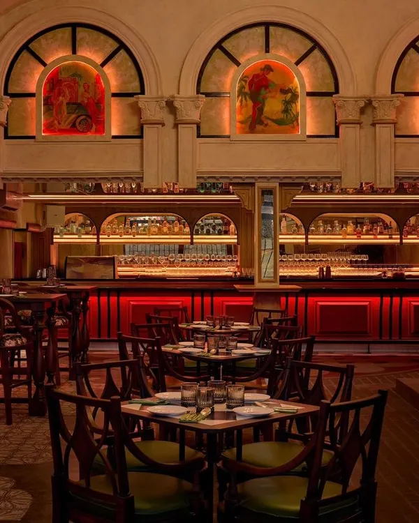 The main dining area of Los Cavos, where the red-lit bar creates a dramatic focal point. The design uses arched windows and warm ambient lighting to craft an intimate yet grand atmosphere, reminiscent of colonial Cuban architecture.