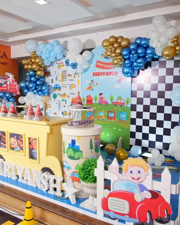 A closer look at the Cocomelon birthday stage, showing the checkered racing flag backdrop panel and a cute car cutout, adding more detail to the transportation theme.