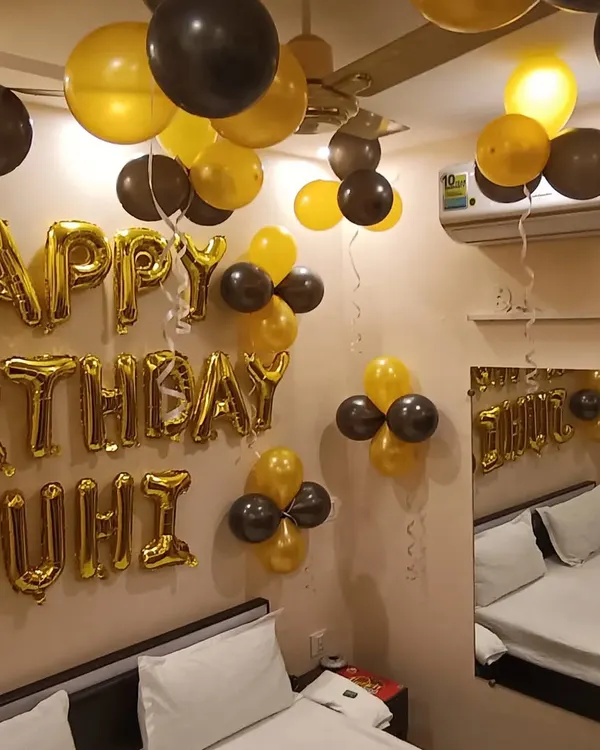 A classic birthday decoration for a bedroom. We used gold and black balloons on the ceiling and wall, with "Happy Birthday" and the name "JUHI" in gold foil letters.