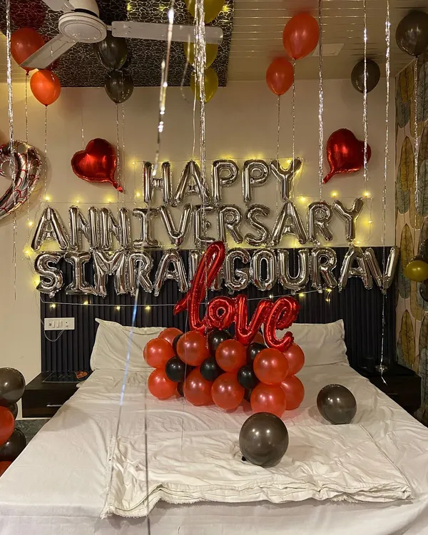 A close-up of a personalized anniversary decoration. I used silver foil balloons to spell out 'Happy Anniversary' along with the couple's names, with fairy lights behind them for a soft glow. The 'Love' balloon and other heart foils complete the theme.