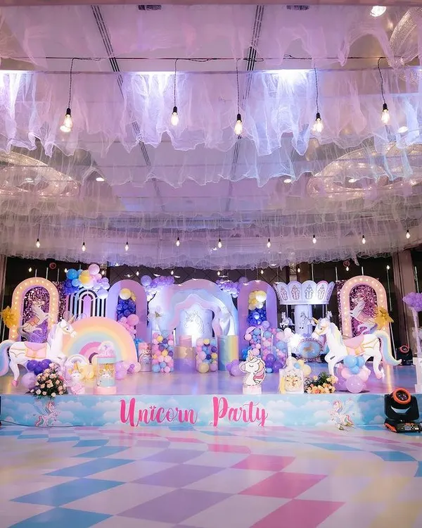 This is what a unicorn dream looks like! We created this entire magical world for a birthday party, complete with a custom stage, life-sized unicorn props, a pastel rainbow floor, and a dreamy ceiling with soft drapes and lights.