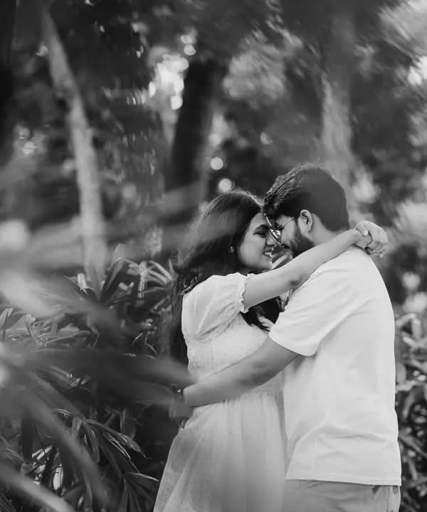 A beautiful black and white shot of a couple embracing in a garden. The monochrome tones and natural framing create a timeless and romantic feel.