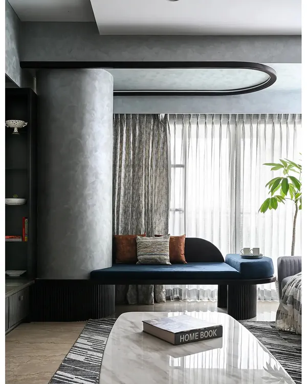 We believe architectural challenges are design opportunities. This custom-designed curved seating, finished in a bold blue fabric, elegantly wraps around a structural column, transforming it from an obstruction into a stunning and functional focal point in the living room.