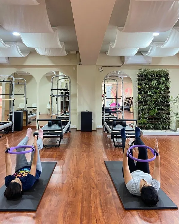 A mother and daughter enjoy a synchronized mat Pilates session using the magic circle. This wide shot captures the harmony and shared focus in our beautiful studio space.