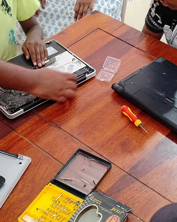Teamwork makes the dream work. Here, kids collaborate to disassemble and inspect laptops during a summer camp workshop. They learn to identify different components and understand how they function together.
