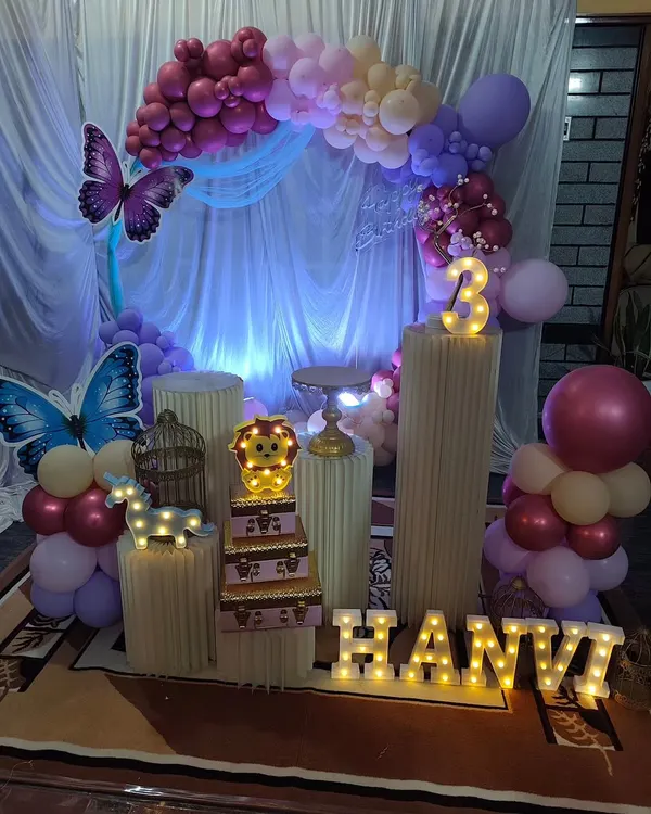 This butterfly-themed party for a 3rd birthday used a soft purple and pink color palette. The setup includes a circular balloon arch, marquee letters for the name, and delicate butterfly accents.