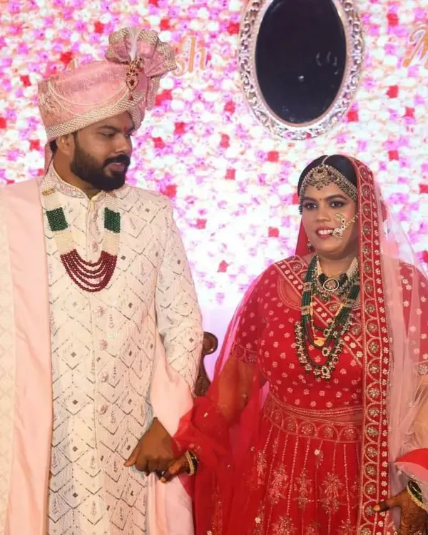 A classic groom look, featuring an off-white Lakhnavi sherwani with intricate embroidery, paired with a pink safa (turban) and dupatta to coordinate with the bride's attire.