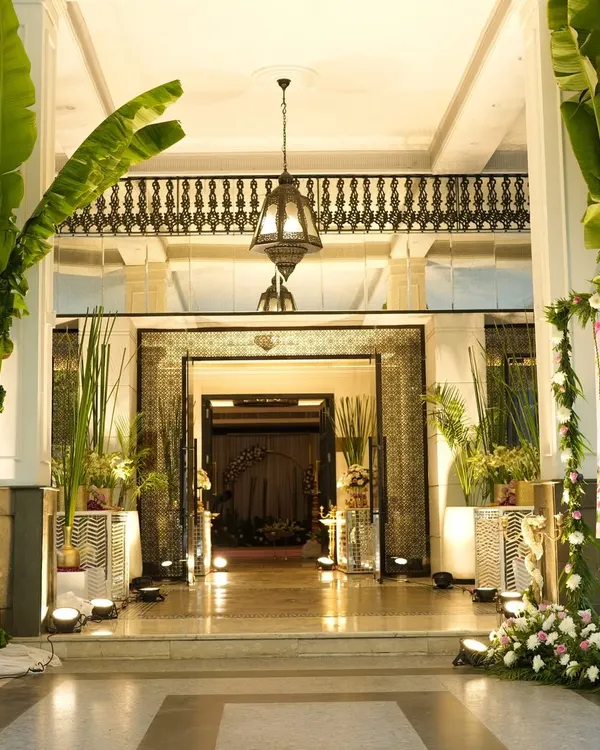 Creating an inviting entrance is key. For this wedding, I used large banana trees, traditional brass lamps, and mirror consoles, all highlighted with pink and white flowers to set a grand and welcoming tone.