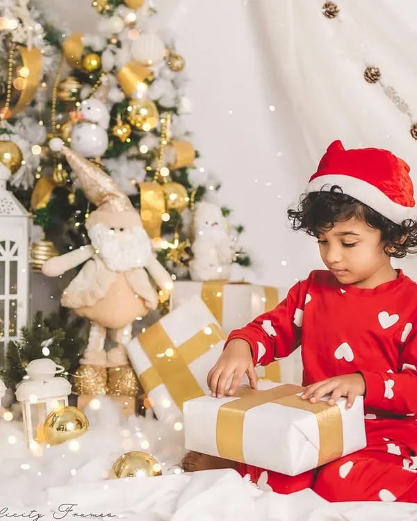 The magic of Christmas morning. This little one is captured in a moment of wonder, opening presents in a beautiful, festive setup.
