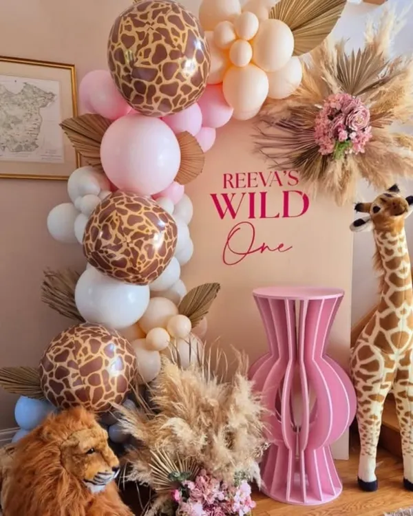 A chic and modern take on the "Wild One" theme, combining giraffe-print balloons with soft pinks, pampas grass, and adorable stuffed animals for a stylish first birthday.