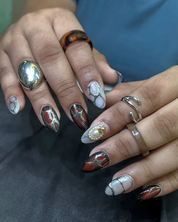 This set is all about texture and detail. I combined a tortoise-shell effect with a cracked stone look and added 3D silver lines and a pearl accent for a truly unique and edgy manicure.