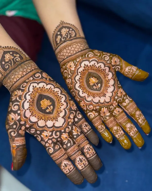 A beautiful Teej mehendi featuring a central lotus mandala. The design is symmetrical and filled with delicate details.