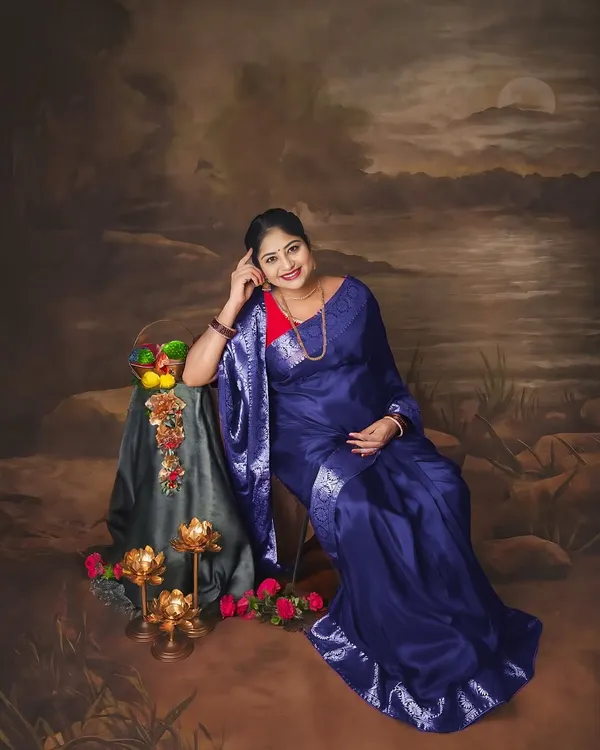 A solo portrait in a beautiful blue silk saree. The pose and the painted backdrop give this photo the feel of a classic piece of art.