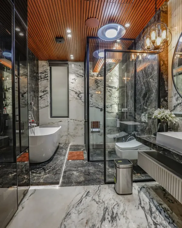 A luxury bathroom in Vikaspuri where I used dramatic black and white marble on both the floors and walls. The space features a freestanding tub, a glass-enclosed shower, and a wooden ceiling for warmth.
